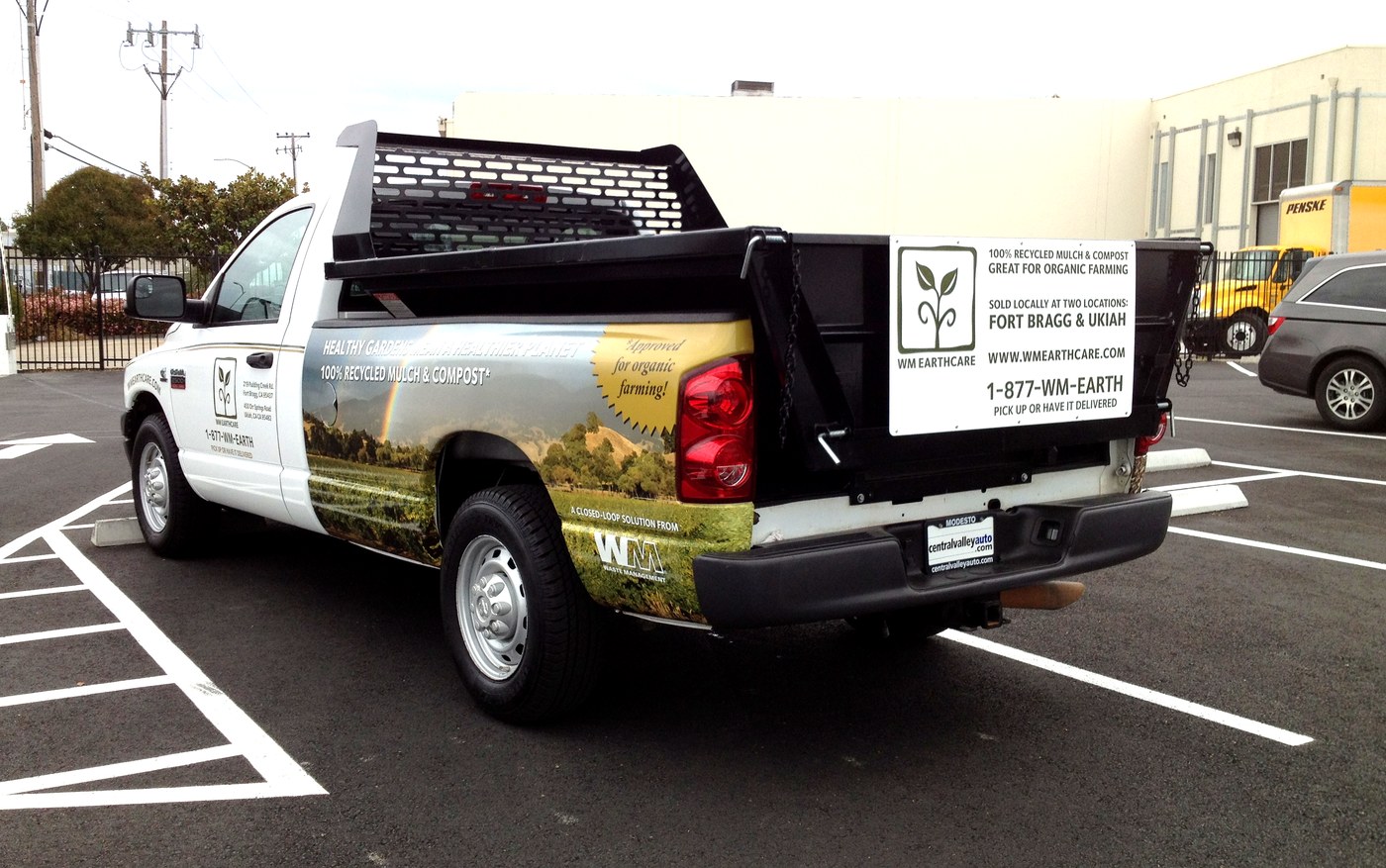 WM EarthCare pickup truck rear three-quarter view — showing full wrap, tailgate panel, Approved for Organic Farming badge, and Closed-Loop Story callout