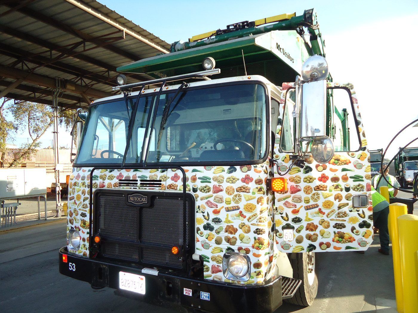 WM EarthCare food-wrap garbage truck — brand identity applied to fleet